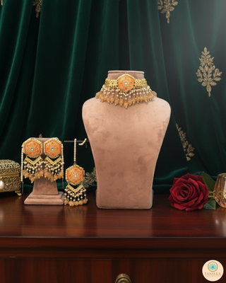Luxury peach-orange meenakari Kundan choker necklace set with matching jhumka earrings and maang tikka, vibrant statement jewelry for South Asian bridal weddings and festive occasions.