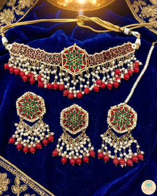 Luxury peach-orange meenakari Kundan choker necklace set with matching jhumka earrings and maang tikka, vibrant statement jewelry for South Asian bridal weddings and festive occasions.