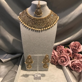 Luxury antique gold finish Kundan bridal necklace set featuring intricate detailing with matching jhumka earrings and maang tikka, elegant statement jewelry for South Asian weddings and nikah ceremonies, as seen in www.taniska.com