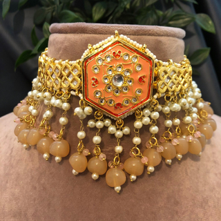 Luxury peach-orange meenakari Kundan choker necklace set with matching jhumka earrings and maang tikka, vibrant statement jewelry for South Asian bridal weddings and festive occasions.