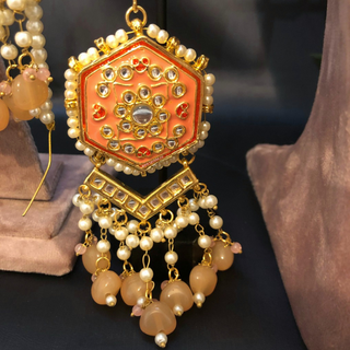 Luxury peach-orange meenakari Kundan choker necklace set with matching jhumka earrings and maang tikka, vibrant statement jewelry for South Asian bridal weddings and festive occasions.